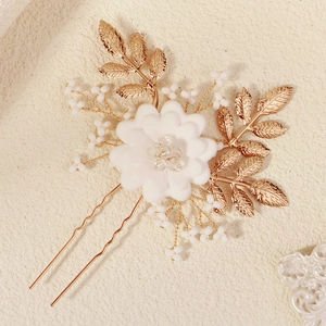 Elegant gold leaf and white flower bridal hair pin with pearls on stone background