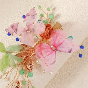 Detail of handmade butterfly hair clip with pink fabric wings and colorful bead accents
