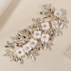 Detail of bridal hair clip with white matte flowers, silver leaves, and crystals