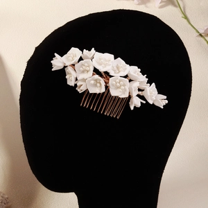 Close-up of white clay floral hair comb with pearls and gold metal base for bridal hair