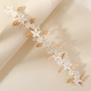 Close-up of handmade bridal headband with gold leaves, white flowers and pearls