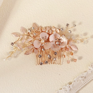 Détail d'un peigne de mariée en or rose avec perles, cristaux et fleurs en métal