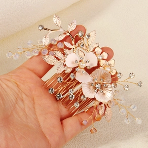 Détail d'un peigne à cheveux de mariée avec fleurs en métal doré, perles et cristaux
