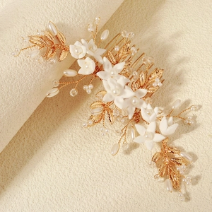 Detailed close-up of handmade white clay flower bridal hair comb with gold wires and pearls