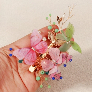 Close-up of handmade fabric butterfly hair clip with gold leaves and pearl details
