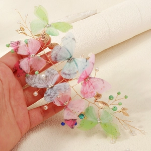 Close-up of handmade butterfly hair clip with gold wire, crystals and faux pearls