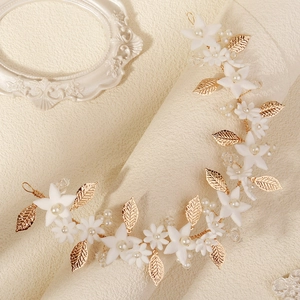 Handmade bridal headband with white clay flowers, gold leaves and pearls on beige texture