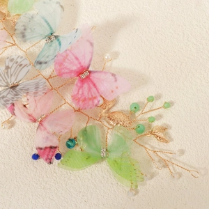 Detailed macro shot of handmade organza butterfly hairpiece with pearls and gold wire