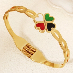 Dettaglio del bracciale a molla in titanio dorato con ciondoli a quadrifoglio smaltati