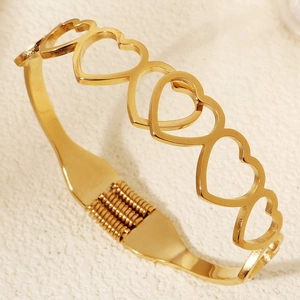Dettaglio del bracciale rigido in acciaio al titanio dorato con motivi a cuore cavo intrecciati