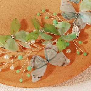 Detailed macro view of handmade mesh butterfly hair clip with pearls and silver leaves