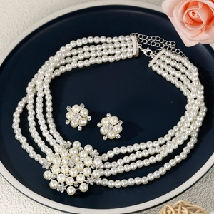 Détails d'un collier de perles à quatre rangs avec fleur en strass et boucles d'oreilles