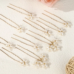 Dettaglio di 12 forcine dorate per sposa con fiori di perle su uno sfondo estetico morbido