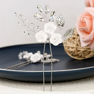 Detail of bridal hair pin with white ceramic flowers, crystal beads and silver leaves