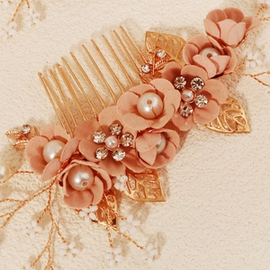 Close-up of pink chiffon flowers and faux pearls on a golden hair comb for bridal styling