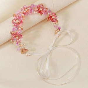 Detail of pink acrylic flowers and pearls on a gold wire bridal headband with ribbons