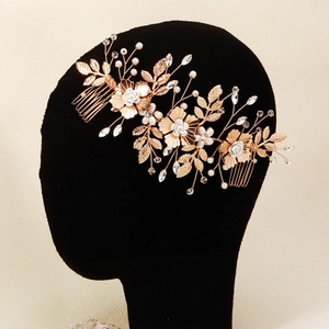 Détail d'un peigne de mariée avec feuilles dorées, perles blanches et cristaux brillants