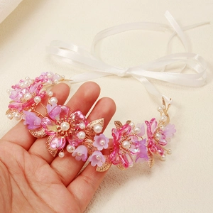Detail of bridal headband with pink acrylic flowers, pearls and golden metal leaves