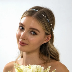 Elegant bridal headband with blue stones and pearls on a model holding white flowers