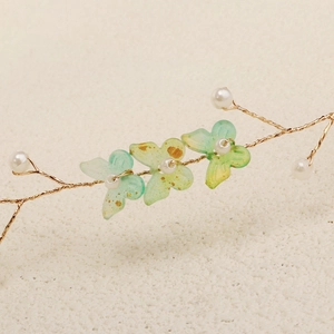 Detailed macro view of handmade gold wire hairband with green resin butterflies and pearls