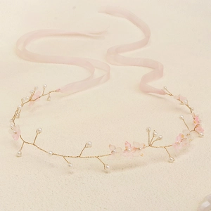 Close-up of handmade bridal headband with pink petals, white pearls and silk ribbons