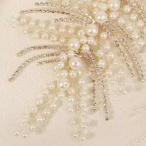 Macro shot of bridal hairpiece showing handmade white pearls and sparkling rhinestones details