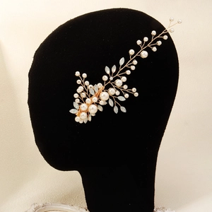 Detailed shot of handmade pearl and crystal bridal hair clip on a black mannequin head