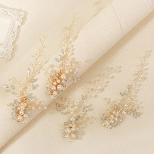 Detailed macro shot of handmade pearl and blue bead bridal hair clips with golden wire