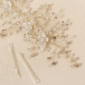 Detail of silver bridal hair vine with white flowers, pearls, and crystals on beige texture
