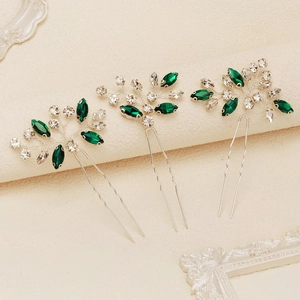 Macro detail of bridal hair pins with green marquise rhinestones and silver wiring