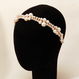 Detailed close-up of handmade faux pearl headband with elegant gold wire weaving