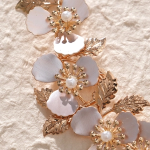 Macro di cerchietto da sposa con foglie dorate e fiori smaltati con perle bianche