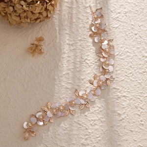 Dettaglio di accessorio sposa floreale con fiori rosa, perle e foglie dorate