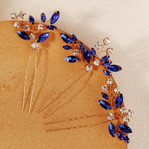 Detail of three handmade gold hair pins with navy blue marquise rhinestones for bridal styling