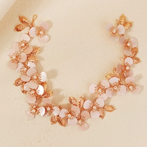 Dettaglio della fascia vintage dorata con petali rosa, perline e foglie di metallo