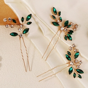 Close-up of handmade gold wire hair pins with green crystals and rhinestones