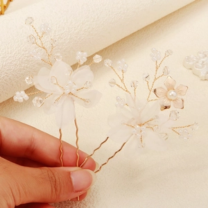 Close-up of handmade bridal hair pins featuring white tulle flowers and pearl beads