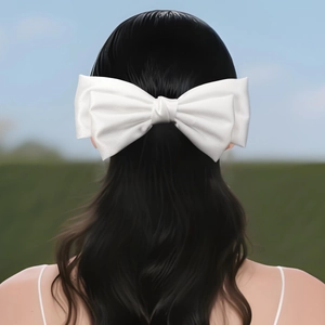 Détail d'un grand nœud en satin blanc avec perles sur des cheveux foncés bouclés vue de dos
