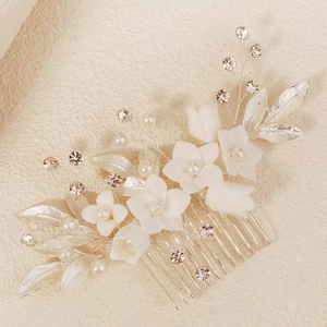 Détail d'un peigne à cheveux de mariée avec fleurs en céramique, perles et feuilles argent