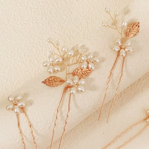 Detail of handmade rose gold hair pins with white pearls and delicate metal leaves