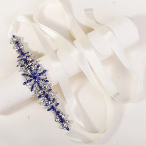 Close-up of elegant bridal sash featuring deep blue rhinestones on a white satin ribbon