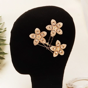 Gros plan détaillé de trois épingles à cheveux de mariée avec fleurs dorées et strass
