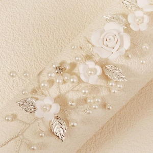 Detail of bridal headband with handmade white clay flowers and silver metal leaves