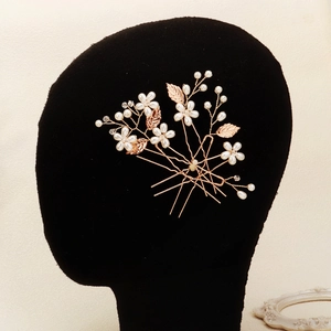 Exquisite bridal hair pin set with pearls and rose gold leaves on a dark hair model