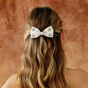 Barrette nœud blanc élégante pour mariée avec perles et strass sur cheveux bouclés