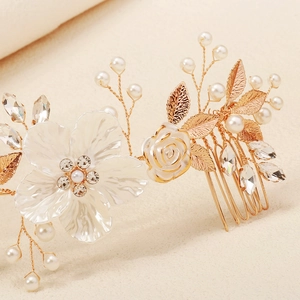 Macro shot of wedding hair comb with white acrylic flowers, pearls and golden leaves