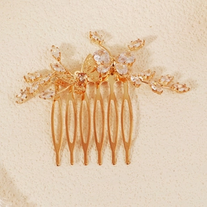Detail of a golden metal bridal hair comb featuring zircon butterflies and floral motifs