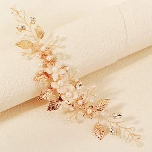 Detail eines handgefertigten Braut-Haarschmucks mit rosa Stoffblumen, Perlen und Goldblättern