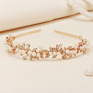 Close-up of gold bridal headband featuring white pearls and rhinestone leaf accents