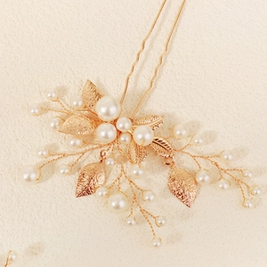 Détail d'une épingle à cheveux de mariée dorée avec perles et feuilles métalliques fines